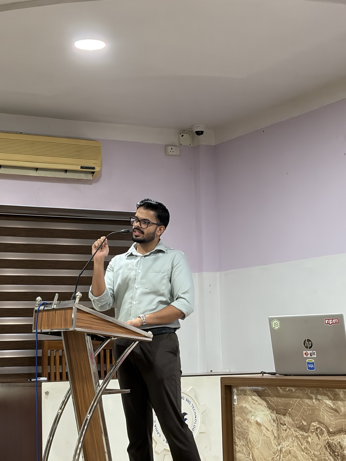 Ameen Abdulsalam speaking into a microphone at a podium during a lecture.